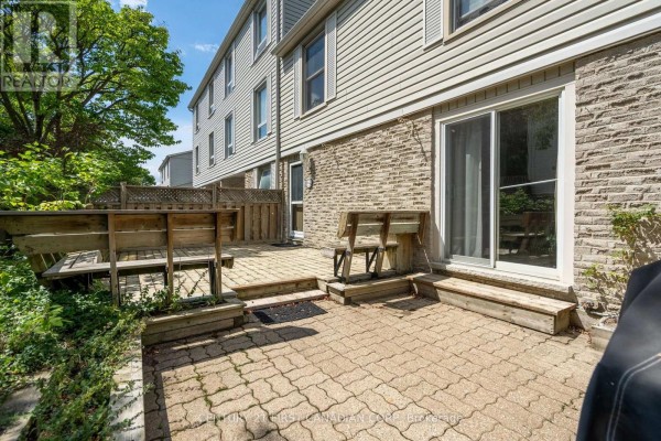 Front view of a townhouse showing the beige siding, stone foundation, and garage door. - 327 Everglade Crescent, London North