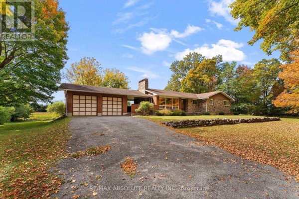 A paved driveway leads to a stone and brick house with a two-car garage on a tree-lined property. - 327 Nieman Drive, Mcnab/braeside