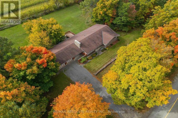 Aerial view of a long, ranch-style house surrounded by colorful autumn trees. - 327 Nieman Drive, Mcnab/braeside