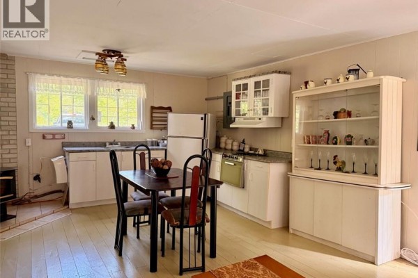 Kitchen and dining area with white cabinets, a refrigerator, and a dining table. - 355 St Maure Road, Balmoral