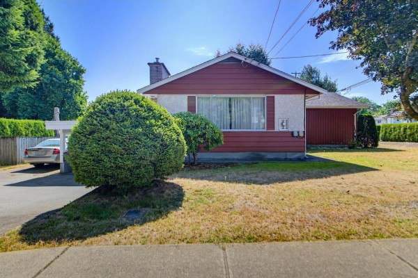 Front view of red sided house with white trim, large bush, and carport. - 32712 Bevan Avenue, Abbotsford