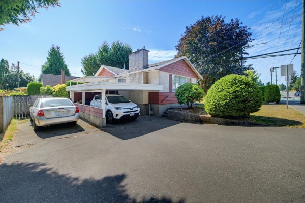 Driveway with two cars parked under carport, next to red sided house. - 32712 Bevan Avenue, Abbotsford
