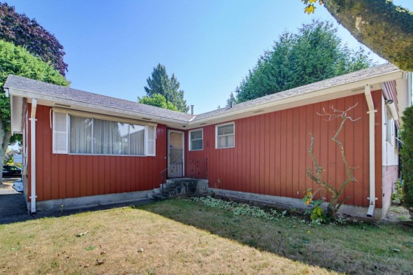 Back side of red sided house with lawn, weeds, and a drain pipe. - 32712 Bevan Avenue, Abbotsford