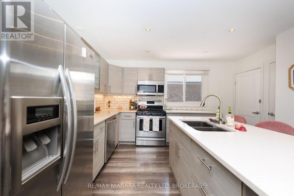 Contemporary kitchen with light grey cabinetry, white subway tile backsplash, and stainless steel appliances. - 3273 Addison Avenue, Niagara Falls