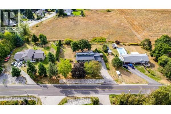 Aerial view of a residential property with a long driveway, pool, and surrounding trees. - 3275 Upper Mcleod Road, Spallumcheen