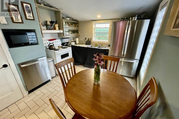 Kitchen and dining area with a wooden table, white stove, and stainless steel appliances. - 32756 Route 2, Springhill