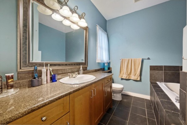 Bathroom featuring blue walls, granite countertop, and a soaking tub - 32758 Lightbody Street, Mission