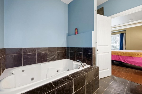 Jacuzzi tub with dark tile surround and adjoining bathroom entrance - 32758 Lightbody Street, Mission