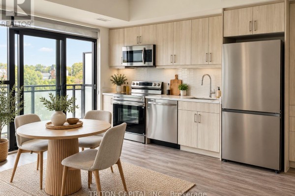Kitchen with light wood cabinets, stainless steel appliances, and a round dining table with chairs. - 328 - 350 Prince Charles Drive S, Welland
