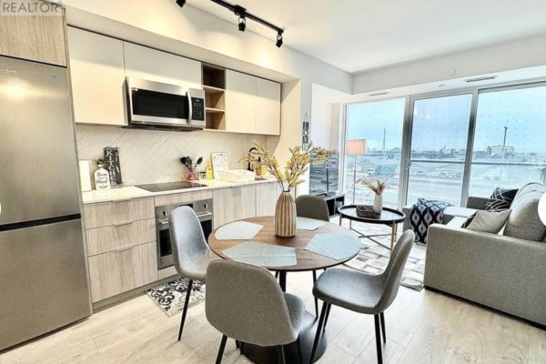 Modern open-concept living area with a compact kitchen, dining table, and sofa. - 328 - 36 Zorra Street, Toronto