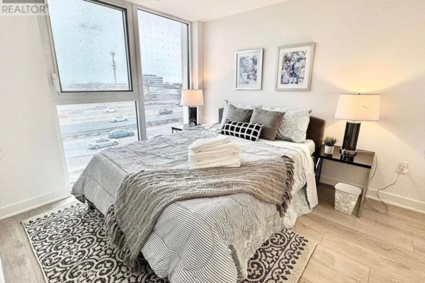 Bedroom with a large window overlooking a highway, a bed, and bedside tables. - 328 - 36 Zorra Street, Toronto
