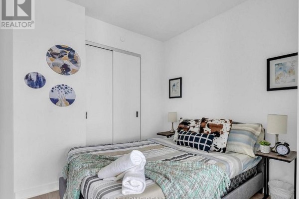 Small bedroom with a bed, sliding closet doors, and decorative circular wall art. - 328 - 36 Zorra Street, Toronto