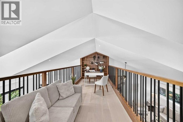 Loft space with couch, desk, chair, and built-in bookshelves under a vaulted ceiling. - 328 3 Street Ne, Calgary