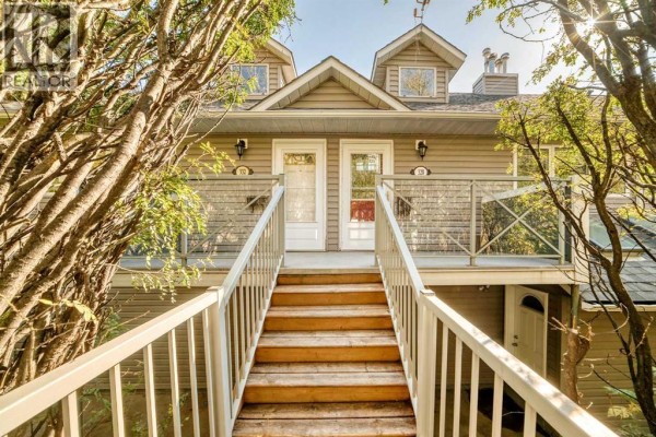 Exterior view of townhouse entrances with wooden stairs leading up to double doors. - 328 3 Street Ne, Calgary