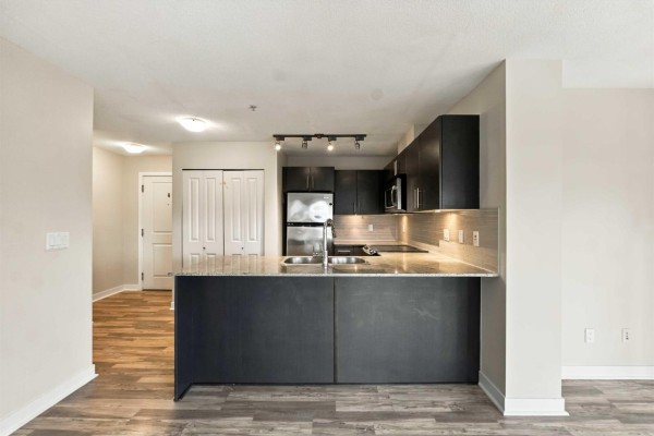 Open concept living and kitchen area with fireplace, large window, and laminate flooring. - 328 8915 202 Street, Langley