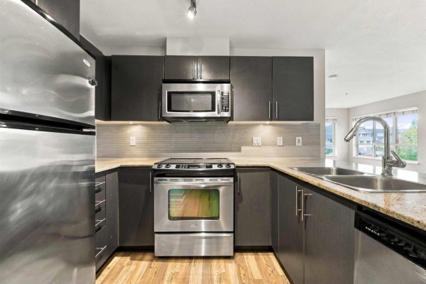 Apartment entrance with double bi-fold closet doors and view into the kitchen. - 328 8915 202 Street, Langley
