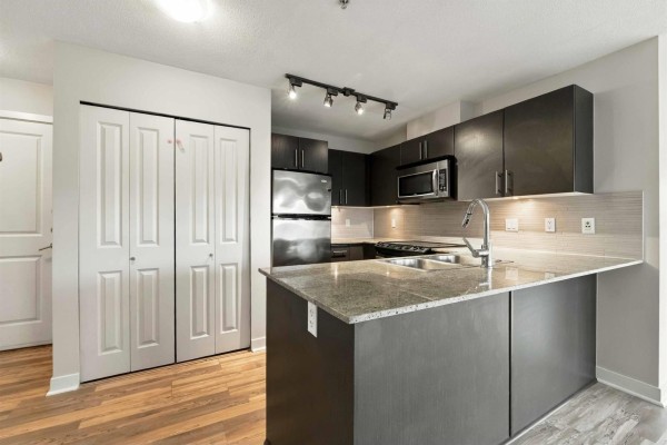 Close-up of the kitchen island with a double sink, faucet, and granite countertop. - 328 8915 202 Street, Langley