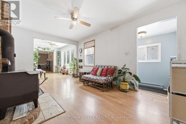 Living room with a wood stove, a sofa, side tables, and wooden shelving. - 32848 Highway 17 Highway, Laurentian Hills