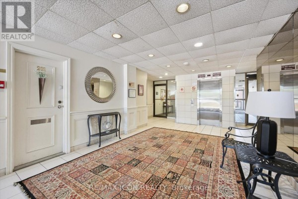 Apartment building lobby featuring a patterned rug, a round mirror, and elevator doors. - 329 - 36 Hayhurst Road, Brantford