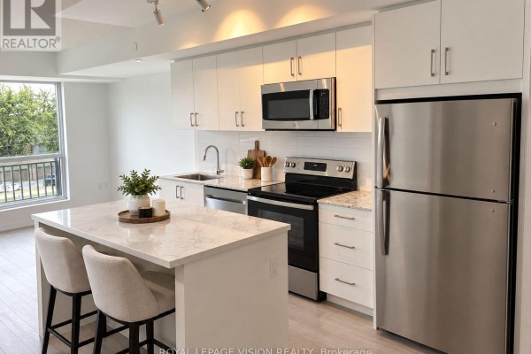 Modern kitchen with white cabinetry, stainless steel appliances, and a marble island with stools. - 329 - 4010 Eglinton Avenue W, Toronto