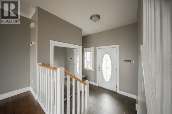 Entrance area with grey walls, a mirrored closet, a small window, and a white oval glass front door. - 329 Archibald Close, Fort Mcmurray