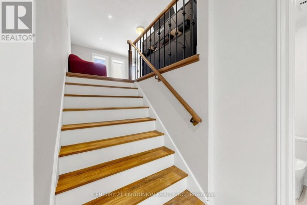 Close-up view of a wooden staircase with white risers and dark metal railings. - 329 Atha Avenue, Richmond Hill