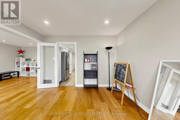 Open concept living area with hardwood floors, connecting to a kitchen through double doors. - 329 Atha Avenue, Richmond Hill