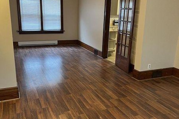 View of an empty room with dark wood laminate flooring and beige walls, showing glass doors. - 329 Ritson Road S, Oshawa