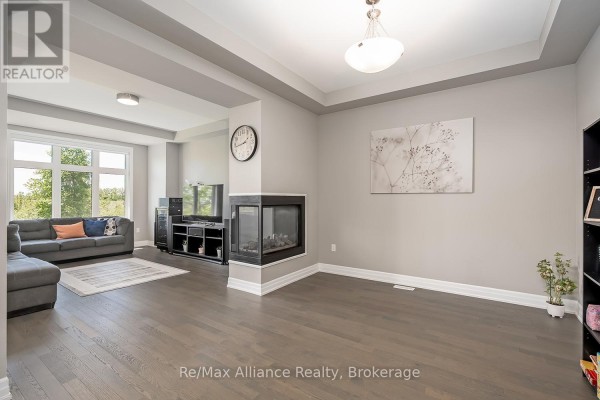 Living room with gray walls, dark wood floors, fireplace, and a sectional sofa. - 3291 Harasym Trail, Oakville