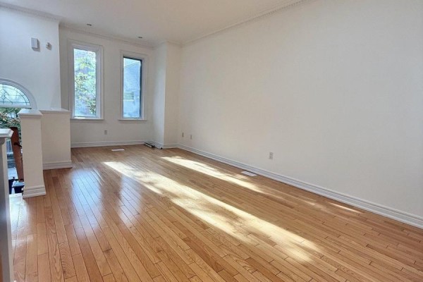 Living room with dark gray sectional sofas, a white coffee table, and a patterned rug. - 32d Oxford Street, Toronto