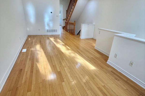 Bright living area with two windows, light wood floors, and gray sofa. - 32d Oxford Street, Toronto