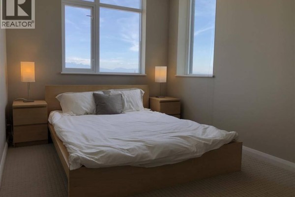 Second bedroom with a minimalist wooden bed frame, nightstands, and beige walls. - 32xx 888 Carnarvon St, New Westminster