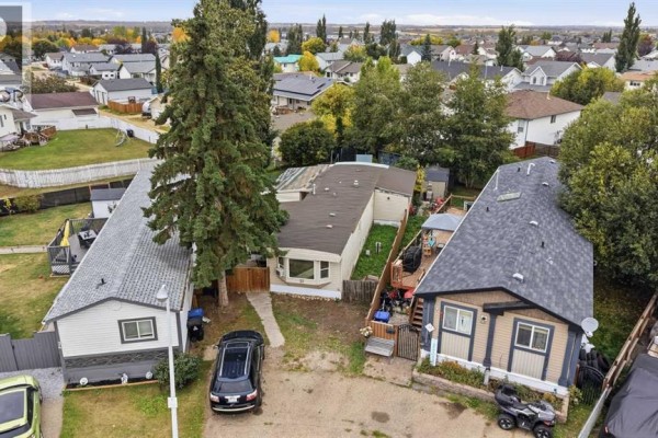 Aerial view of a mobile home situated between two other dwellings on a street. - 33, 4922 Womacks Road Nw, Blackfalds