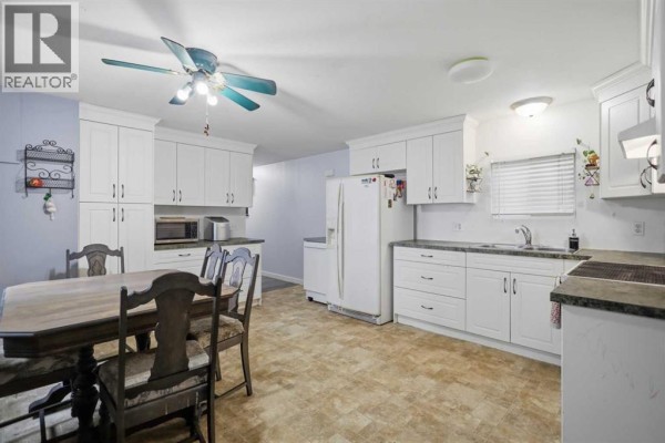 Rear exterior of the beige mobile home showing a backyard with a playset. - 33, 4922 Womacks Road Nw, Blackfalds