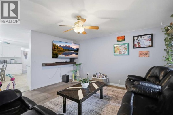 Kitchen and dining area with white cabinets, granite countertops, a wooden table, and chairs. - 33, 4922 Womacks Road Nw, Blackfalds