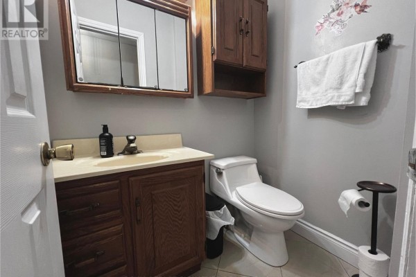 Powder room with a vanity, toilet, mirror, and decorative floral wall art. - 33 - 2301 Derry Road W, Mississauga