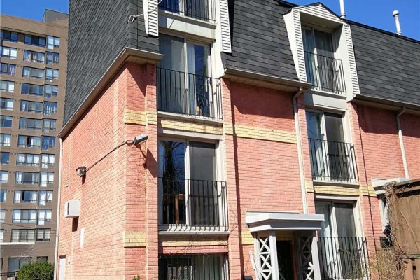 Close-up of corner townhouse with windows, balconies, air conditioning unit, and brick facade. - 33 - 325 Jarvis Street, Toronto
