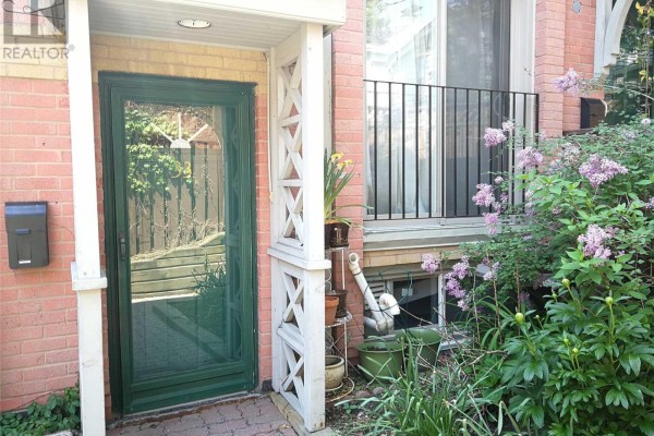 Front entrance of a townhouse with a green door, brick exterior, plants, and window. - 33 - 325 Jarvis Street, Toronto