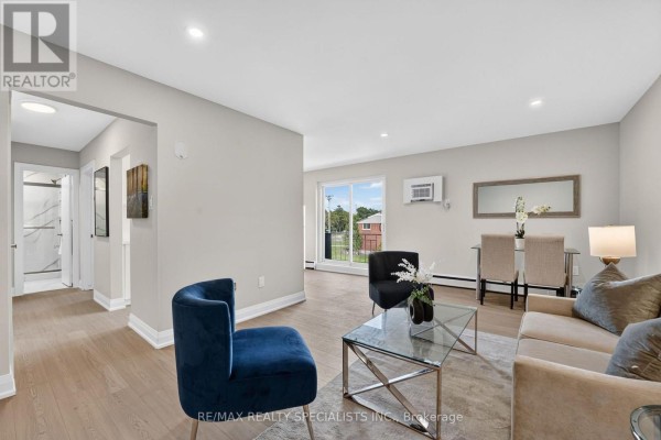 View of the living area, dining area, and hallway to the bathroom, with light grey walls and light wood floors. - 33 - 426 Queenston Street, St  Catharines