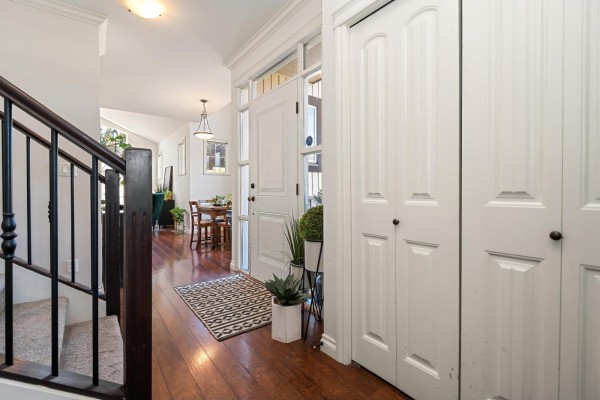 Interior view of a townhouse entryway with dark wood floors, white doors, and a staircase. - 33 6577 Southdowne Place, Sardis South, Chilliwack