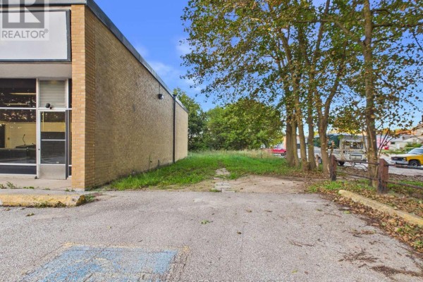 Side exterior of the commercial building showing tan brick and adjacent overgrown lot. - 33 Argyle Street, Grey Highlands