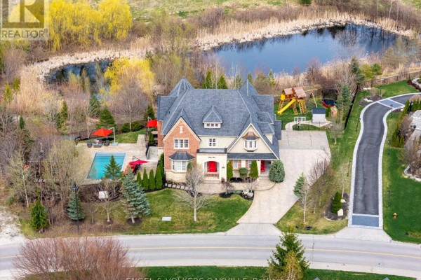 Aerial view of a large brick house with a pond and playground in the backyard. - 33 Barraclough Boulevard, Halton Hills