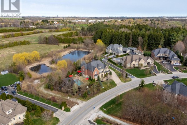 Aerial view of a large estate home and surrounding luxury properties near a pond. - 33 Barraclough Boulevard, Halton Hills