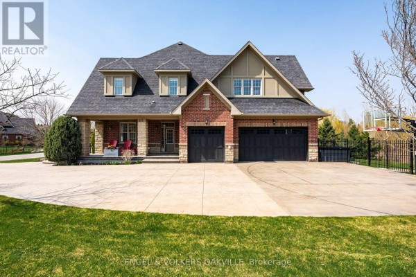 Front view of a large brick house with a three-car garage and covered porch. - 33 Barraclough Boulevard, Halton Hills