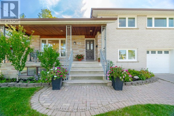 Close-up front view of the house entrance with stone accents, porch, and blooming flower pots. - 33 Belleglade Court, Toronto