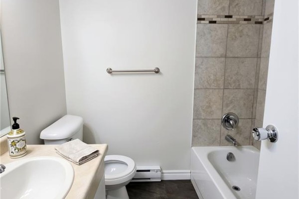 Bathroom with toilet, sink, and bathtub with tiled shower surround. - 33 Cambridge Street Unit# D, Cambridge