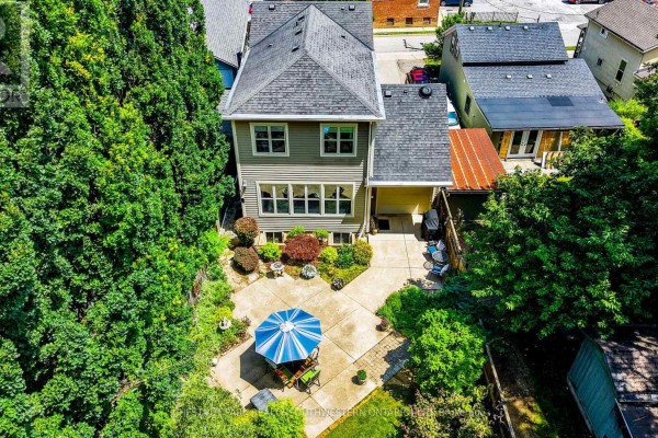Aerial view of the backyard of a house, showing a patio, lawn, trees, and a detached garage. - 33 Cherry Street, St  Catharines