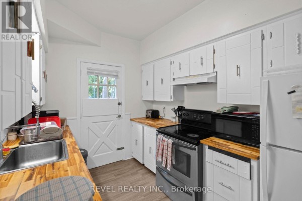 Cozy bedroom with a bed, chair, and closet, light-colored walls, and wooden flooring. - 33 Cline Avenue N, Hamilton