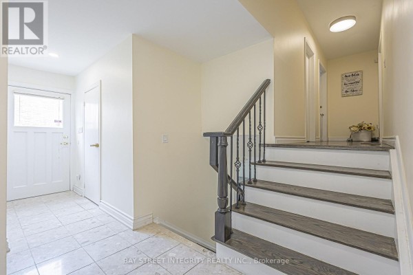 Hallway with tile floor, staircase with dark wood steps and ornate railing - 33 Deerford Road Toronto