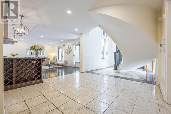 Spacious interior foyer with a large curved staircase, tiled floors, and a wine rack. - 33 Deerford Road, Toronto